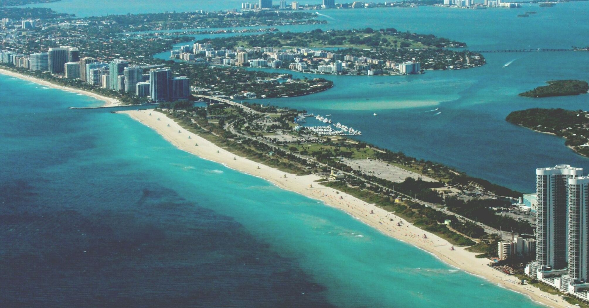 Arial view of Miami coastline with clear blue waters and high-rise buildings