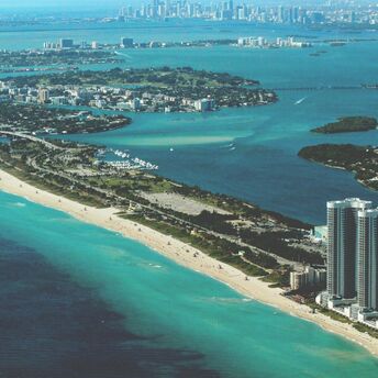 Arial view of Miami coastline with clear blue waters and high-rise buildings