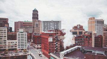 A view of Detroit's downtown with historic and modern buildings, some showing signs of wear, under a cloudy sky