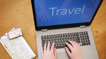 Travel planning with laptop, camera, watch, and map