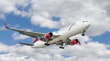 White and red flying airplane under white clouds