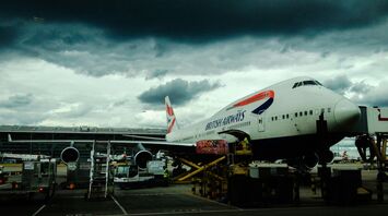 White and red airplane with cumulonimbus cloud