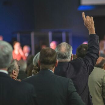 People at a gathering raising their hands in a sign of participation or agreement