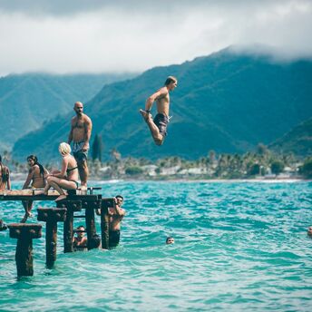 Man diving from dock with people