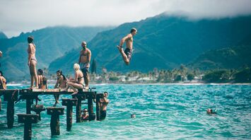 Man diving from dock with people