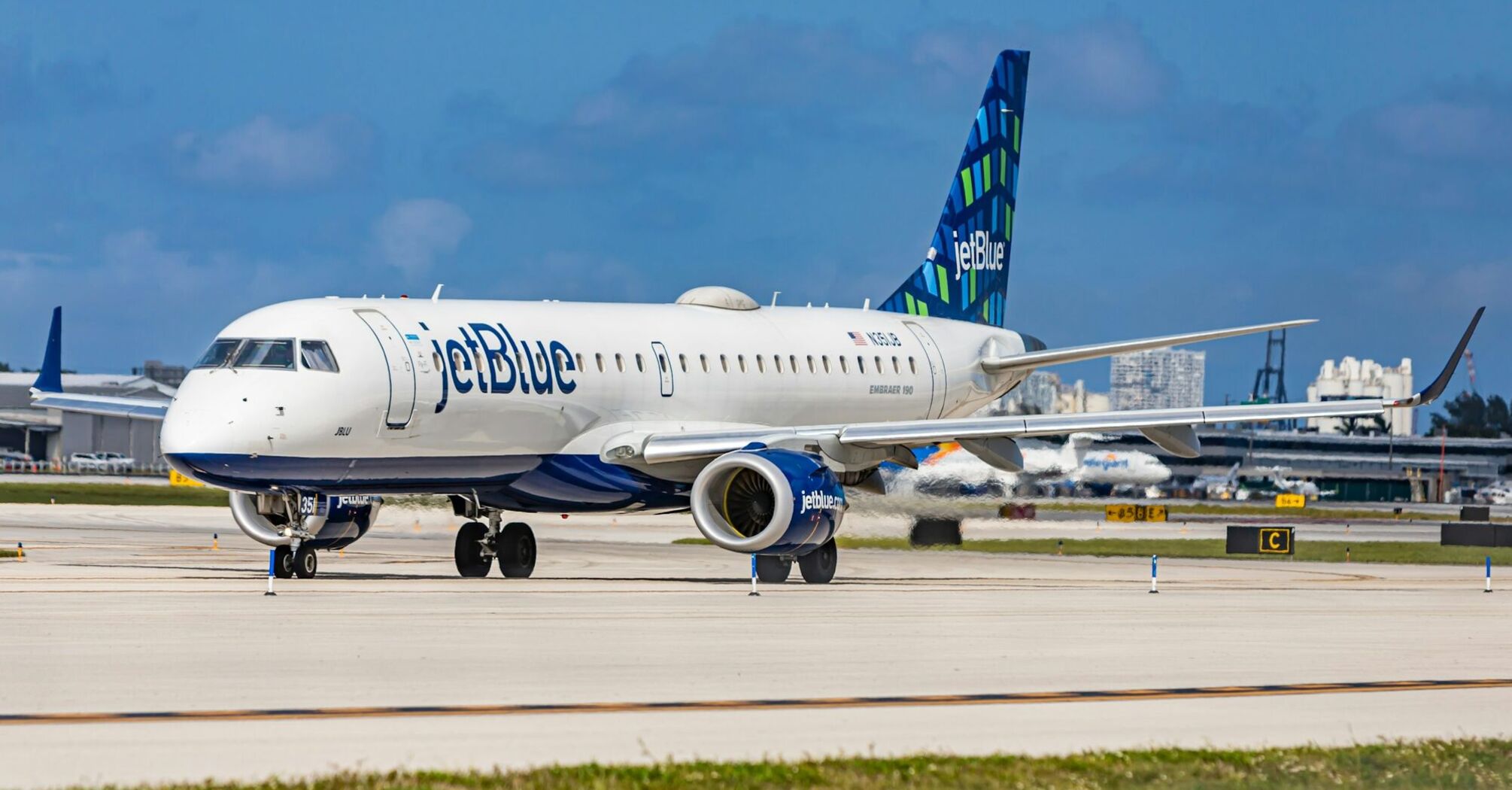 JetBlue Embraer 190 aircraft on the tarmac at an airport with clear skies in the background 
