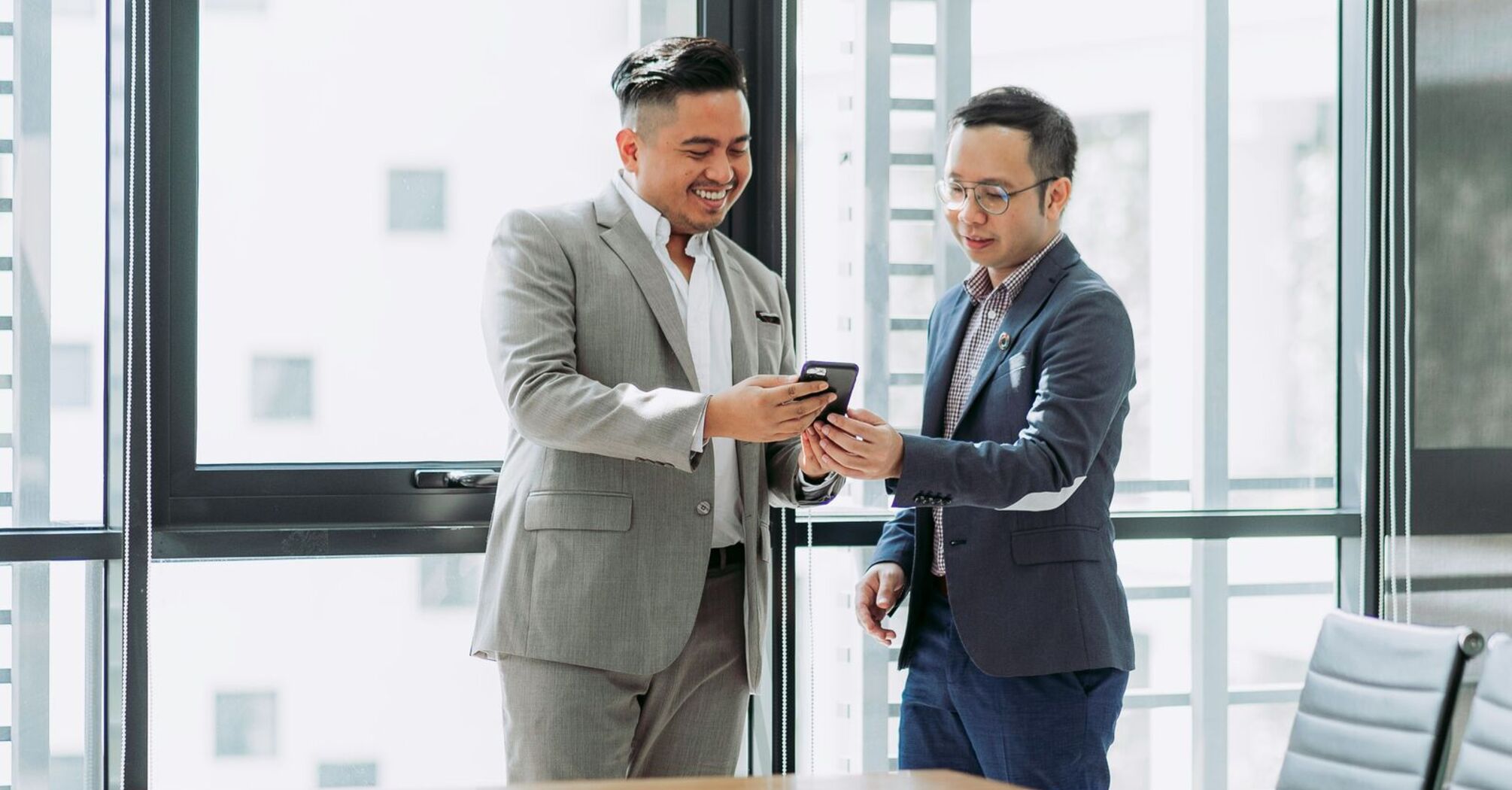 Two men looking at a smartphone in the office