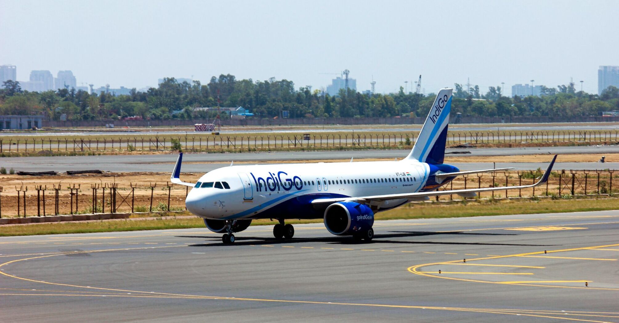 An IndiGo airline aircraft on the tarmac under a clear sky