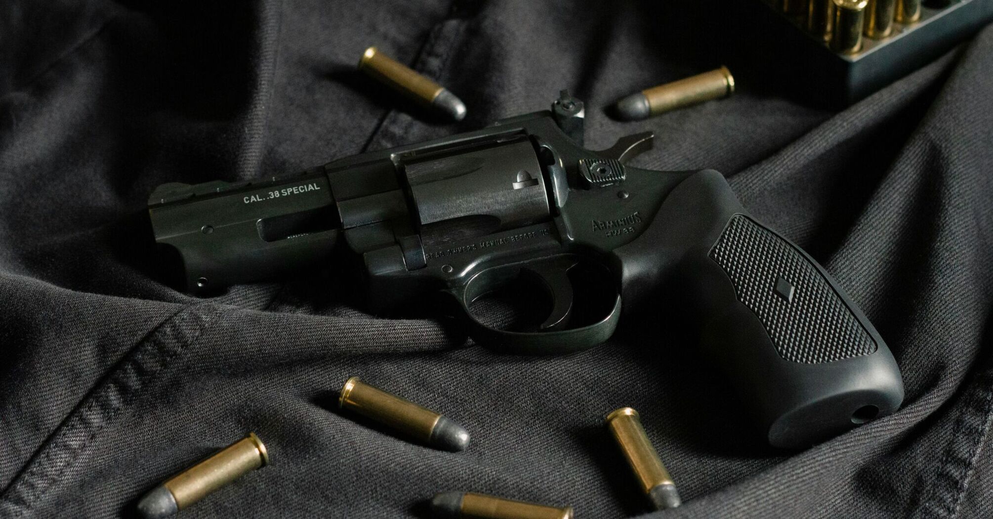 Revolver and bullets on a dark fabric background