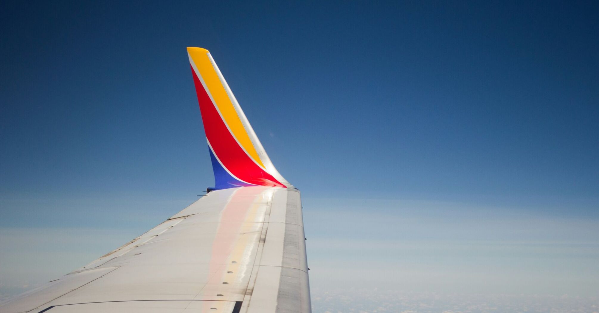 Wing of a Southwest Airlines plane in flight against a clear blue sky