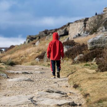 A person in a red jacket walking down a dirt road