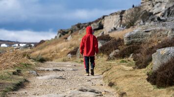 A person in a red jacket walking down a dirt road