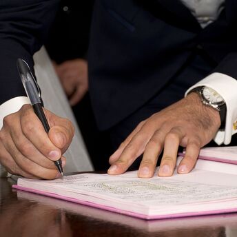 Close-up of a person's hands signing a document on a desk