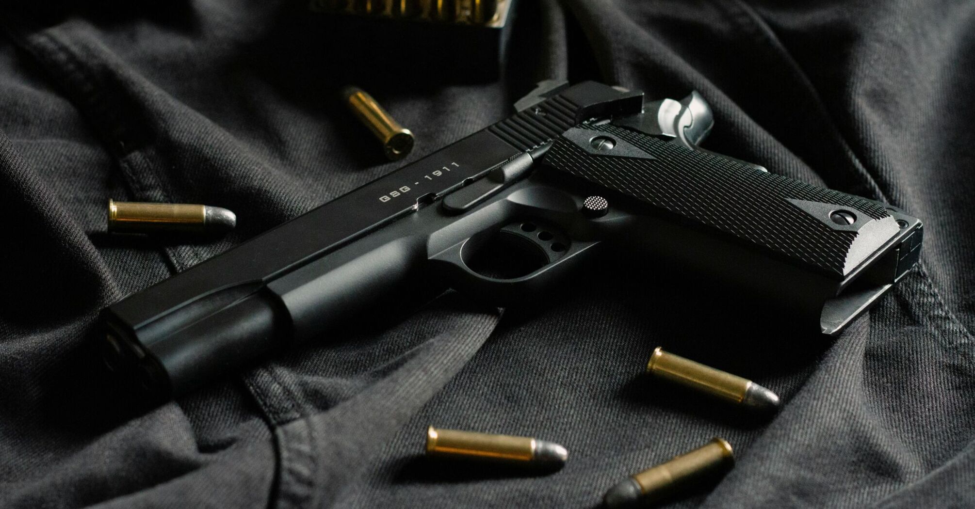 Black handgun with ammunition on dark fabric