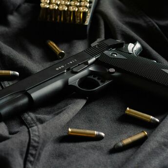 Black handgun with ammunition on dark fabric