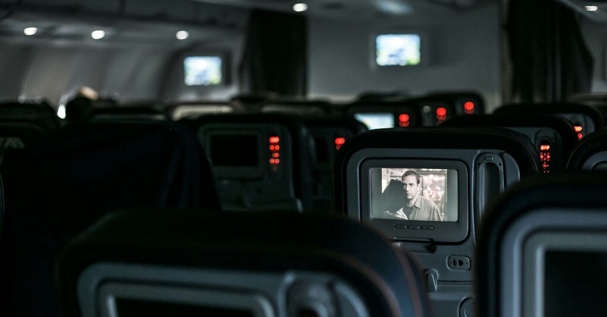 In-flight entertainment screens showing a movie on an airplane