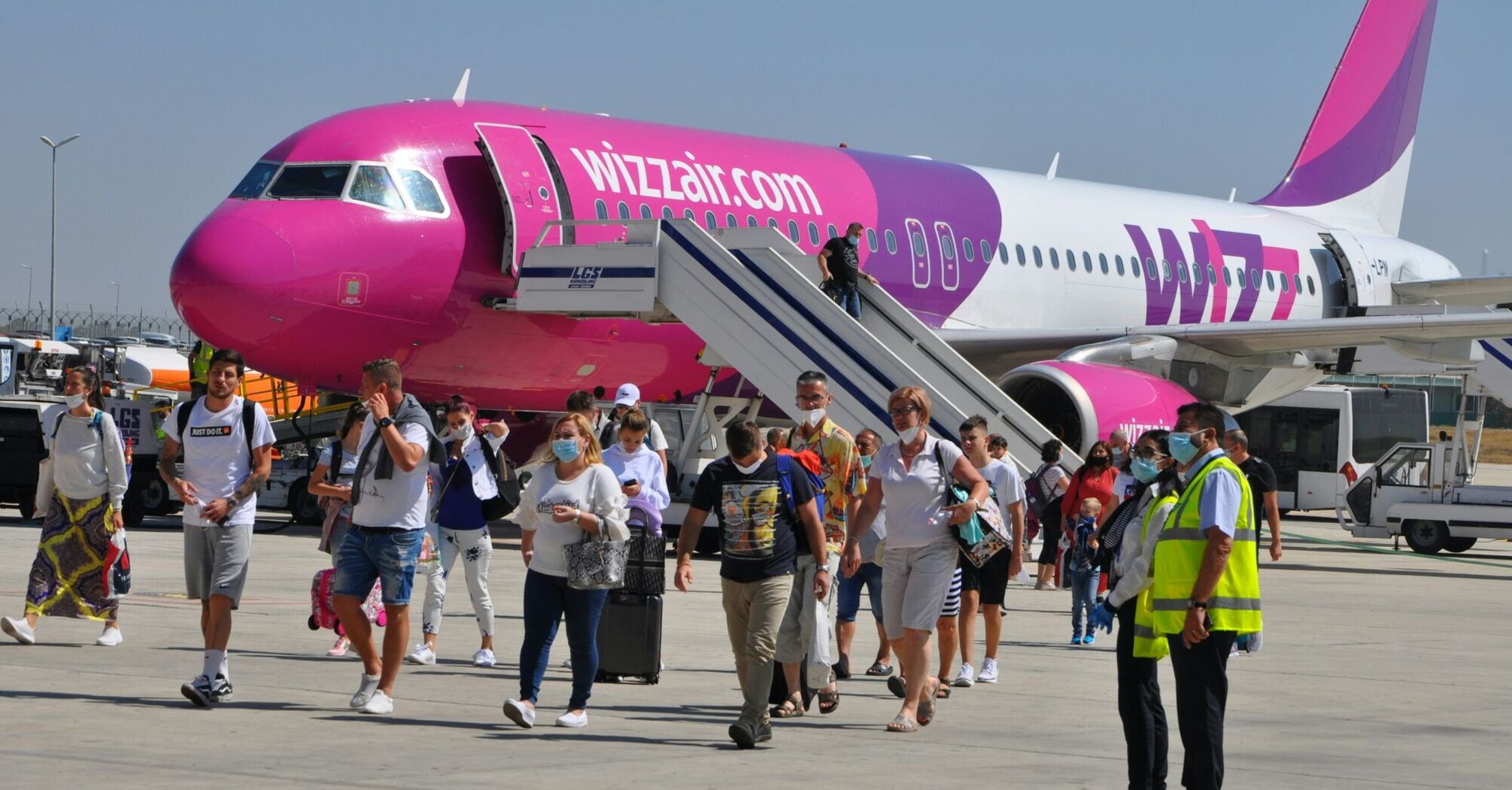 People walking near pink and white airplane during daytime