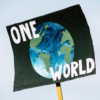 Sign with 'ONE WORLD' and a depiction of Earth, symbolizing global unity