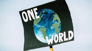Sign with 'ONE WORLD' and a depiction of Earth, symbolizing global unity