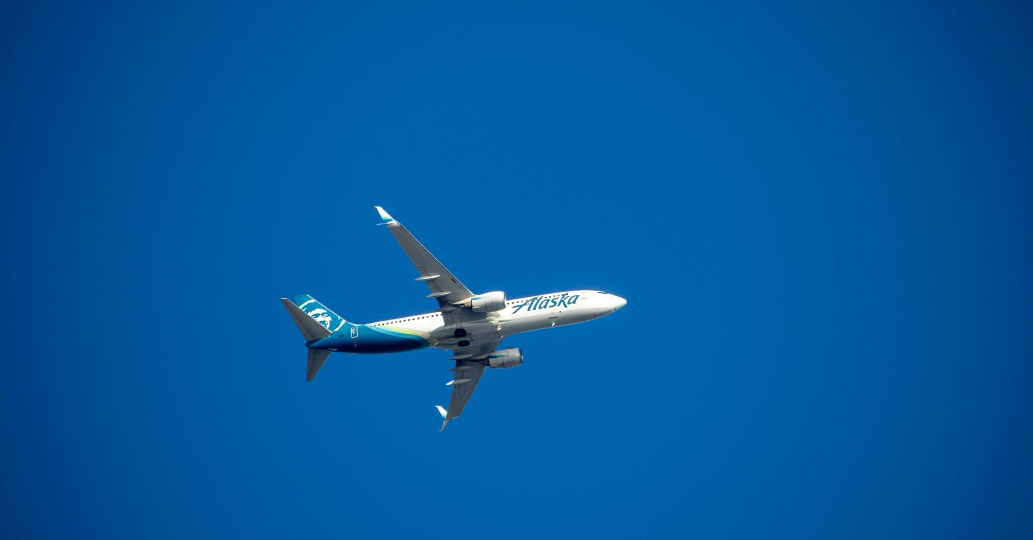 A blue and white airplane flying in a blue sky