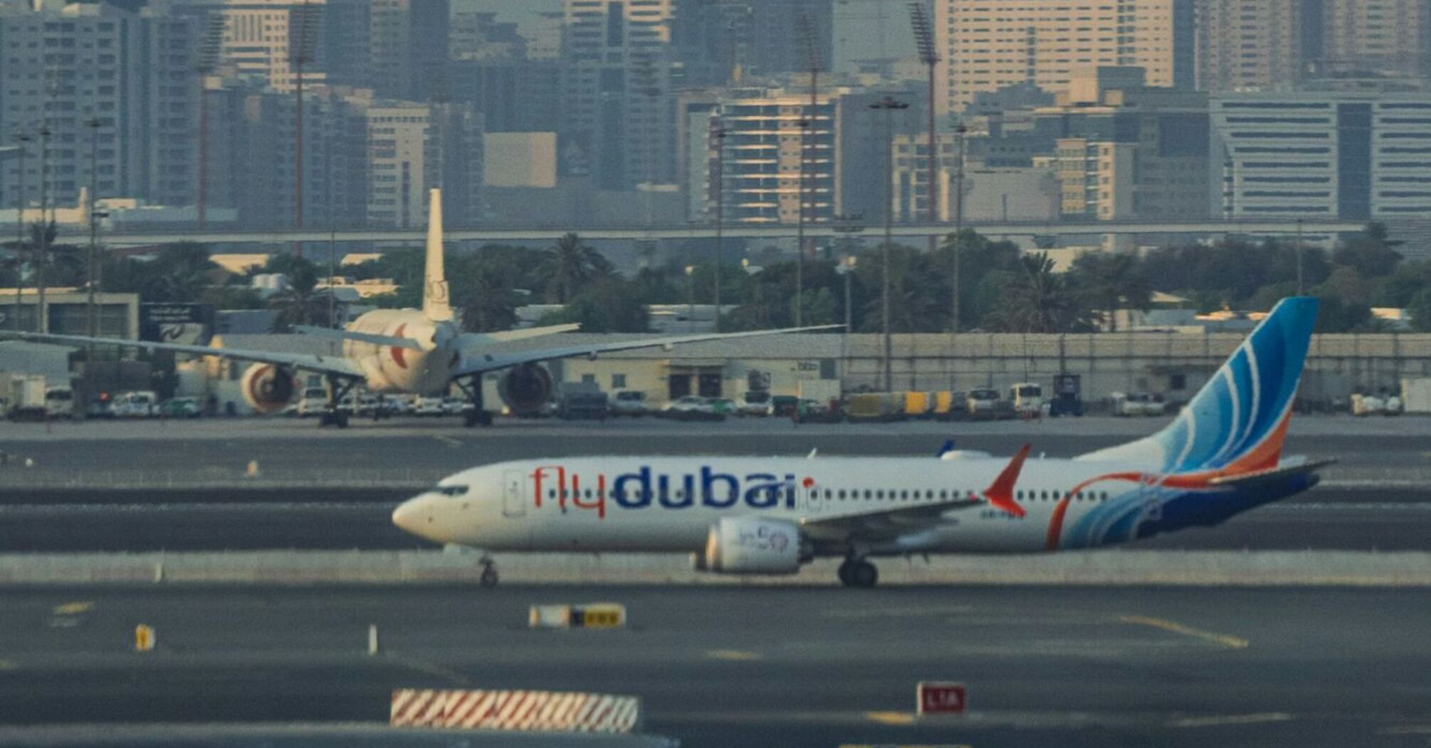 Airplane from flydubai on a runway with city buildings in the background