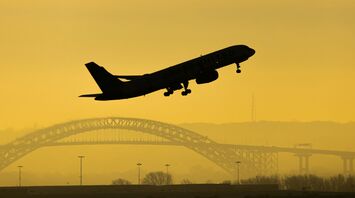 An airplane taking off from Newark Liberty International Airport with a golden sky in the background