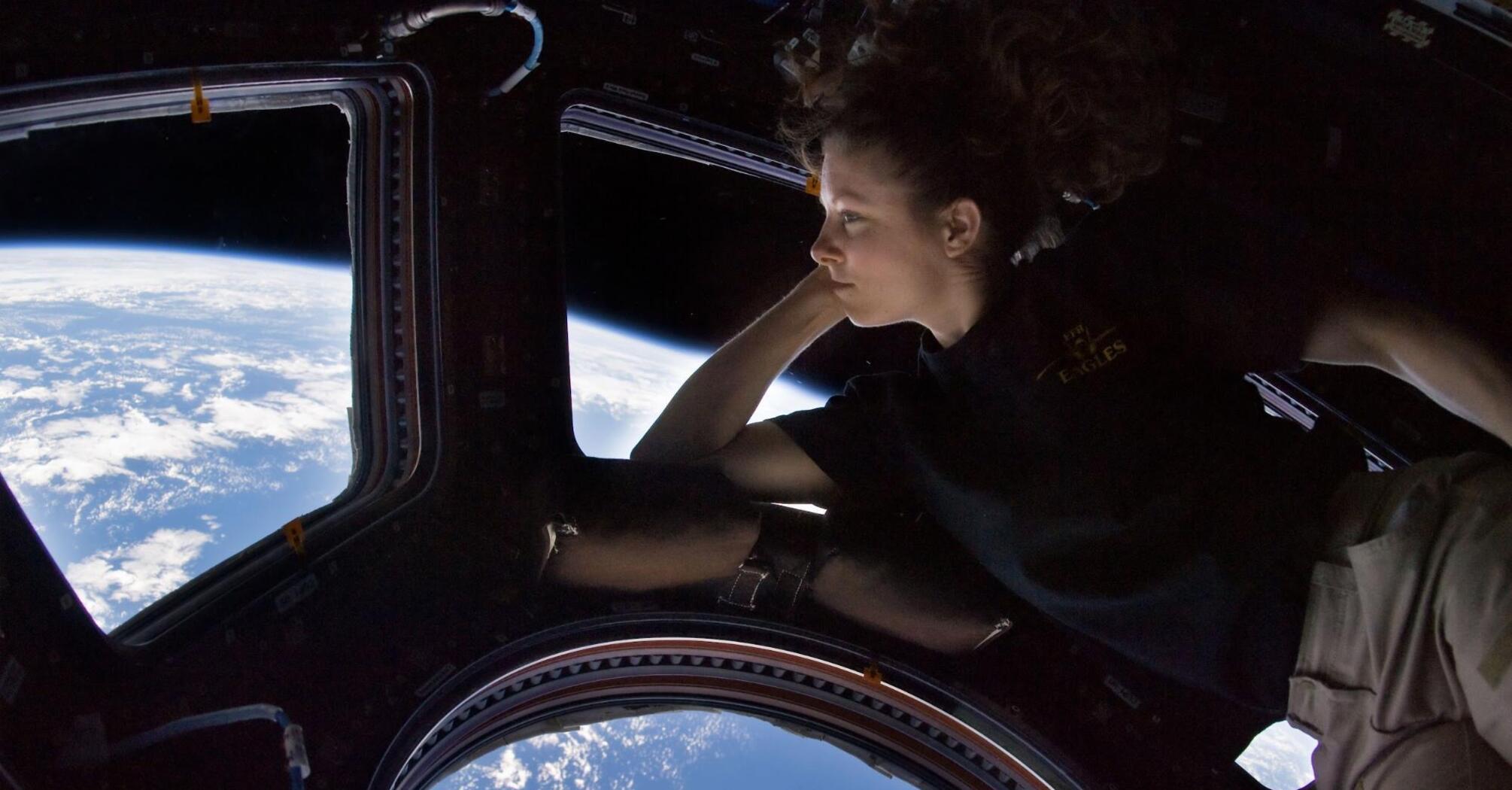 The girl looks out the window of the space porthole
