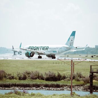 Frontier Airlines plane taxiing on an airport runway with a polar bear design on its tail fin