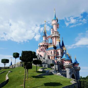 Sleeping Beauty Castle in Disneyland Paris with a blue sky backdrop and neatly greenery