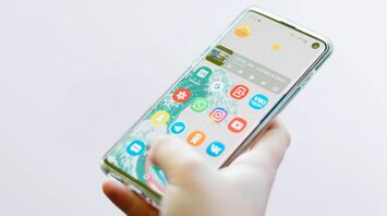 Man holding a mobile phone with applications in his hand