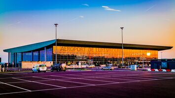 Sunset view of Luxembourg Airport, showcasing its modern architecture and parking area