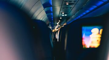 Interior view of an airplane cabin with dim lighting and seatback screens