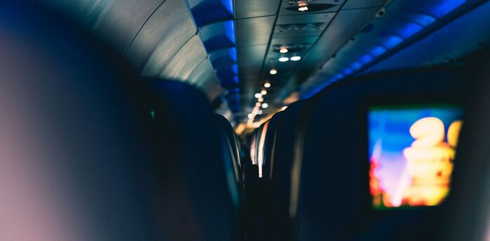 Interior view of an airplane cabin with dim lighting and seatback screens