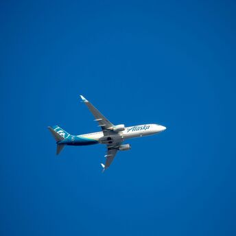 A blue and white airplane flying in a blue sky