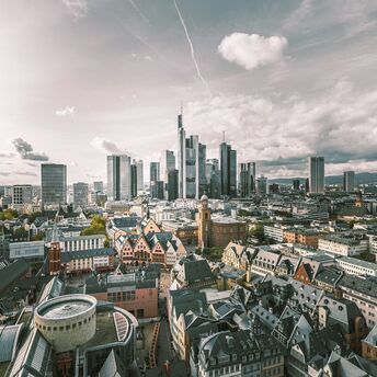 Aerial view of Frankfurt, Germany, with a mix of modern skyscrapers and traditional architecture under a partly cloudy sky