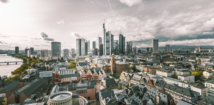 Aerial view of Frankfurt, Germany, with a mix of modern skyscrapers and traditional architecture under a partly cloudy sky
