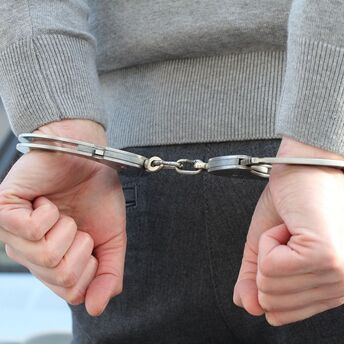 Person in handcuffs with hands behind their back 