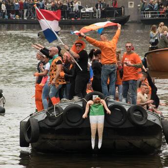 Three boats with people on the river in orange clothes