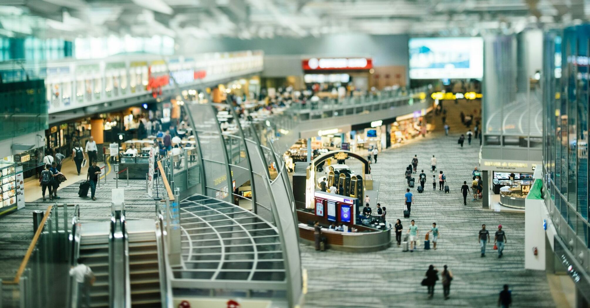 A busy airport terminal with people walking and shopping