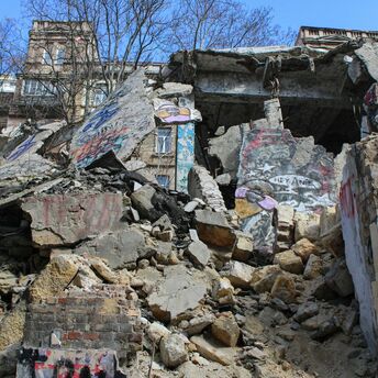 A severely damaged building with collapsed concrete and graffiti