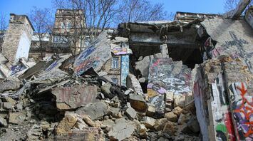 A severely damaged building with collapsed concrete and graffiti