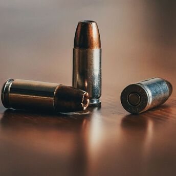 Three 9mm bullets on a wooden surface