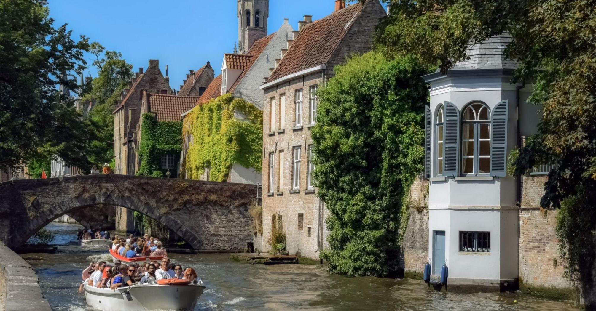 A boat with tourists floats past picturesque houses