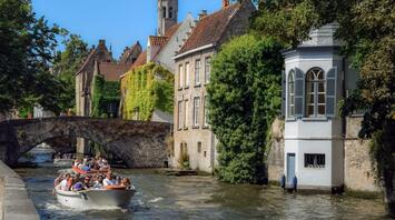 A boat with tourists floats past picturesque houses