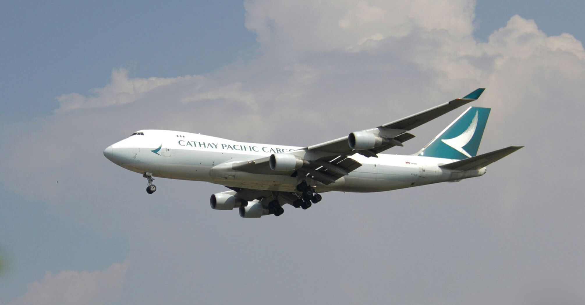 Cathay Pacific cargo airplane in flight against a cloudy sky