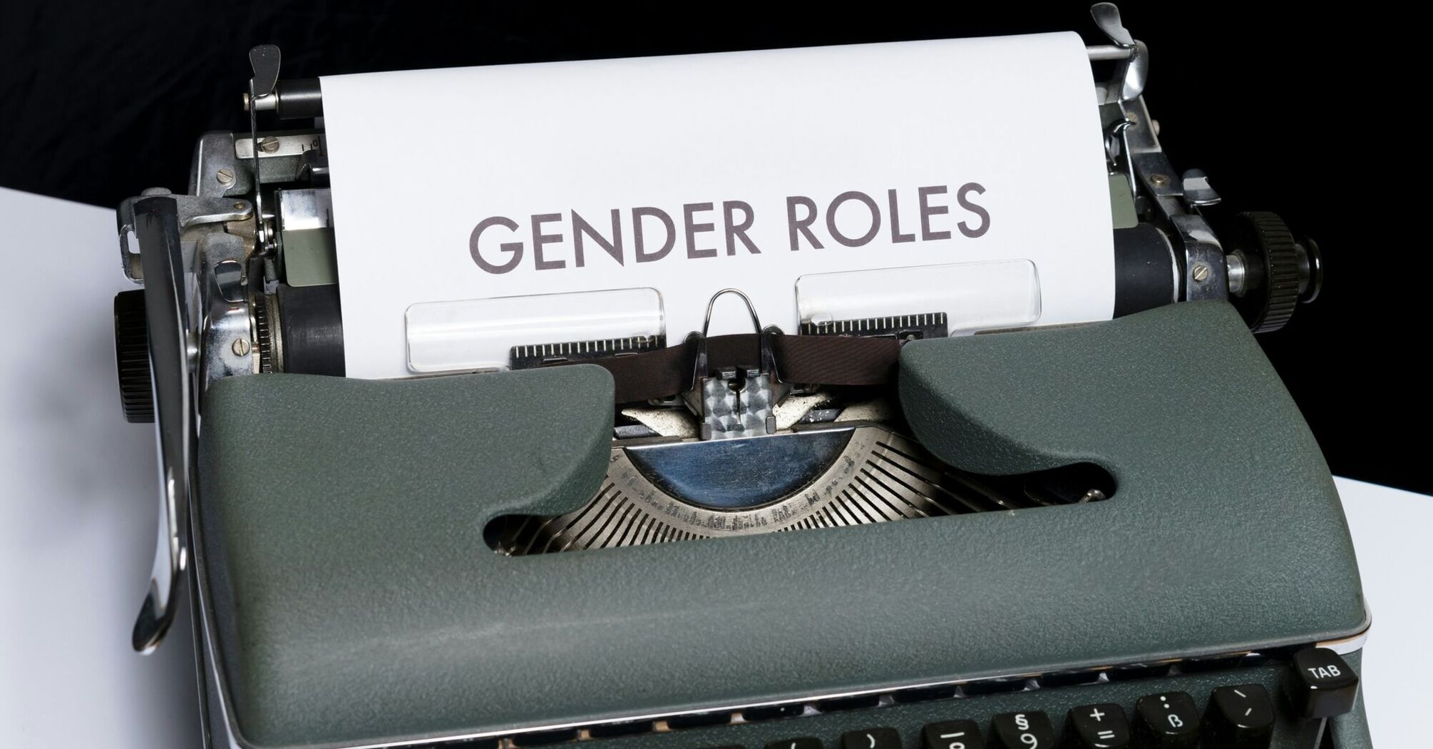 A vintage typewriter with a sheet of paper inserted that has "GENDER ROLES" typed on it