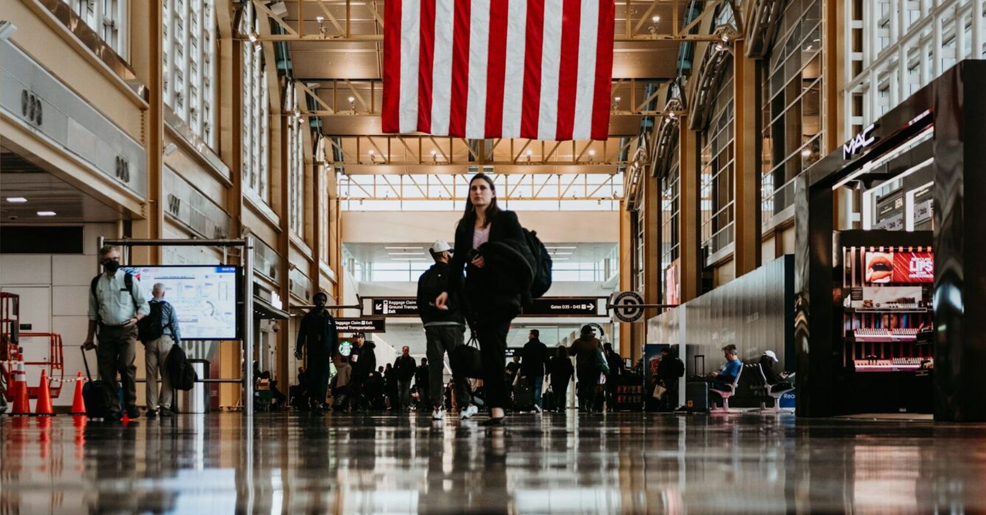 Busy terminal at Reagan National Airport under a large American flag
