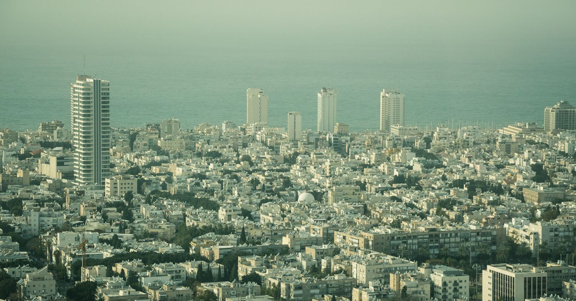 Aerial view of Tel Aviv cityscape with high-rise buildings and the Mediterranean Sea in the distance