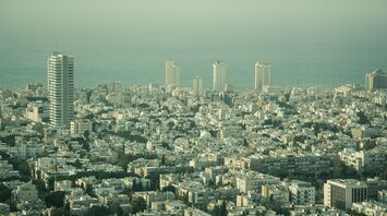 Aerial view of Tel Aviv cityscape with high-rise buildings and the Mediterranean Sea in the distance