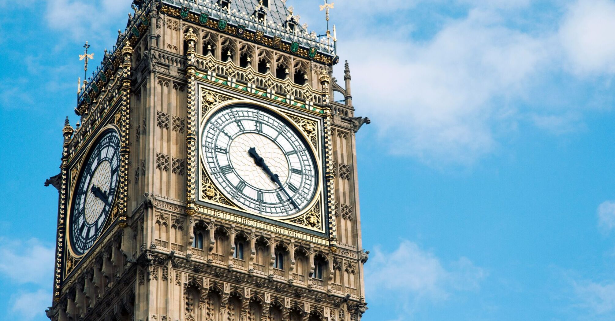 The iconic Big Ben clock tower against a blue sky with white clouds
